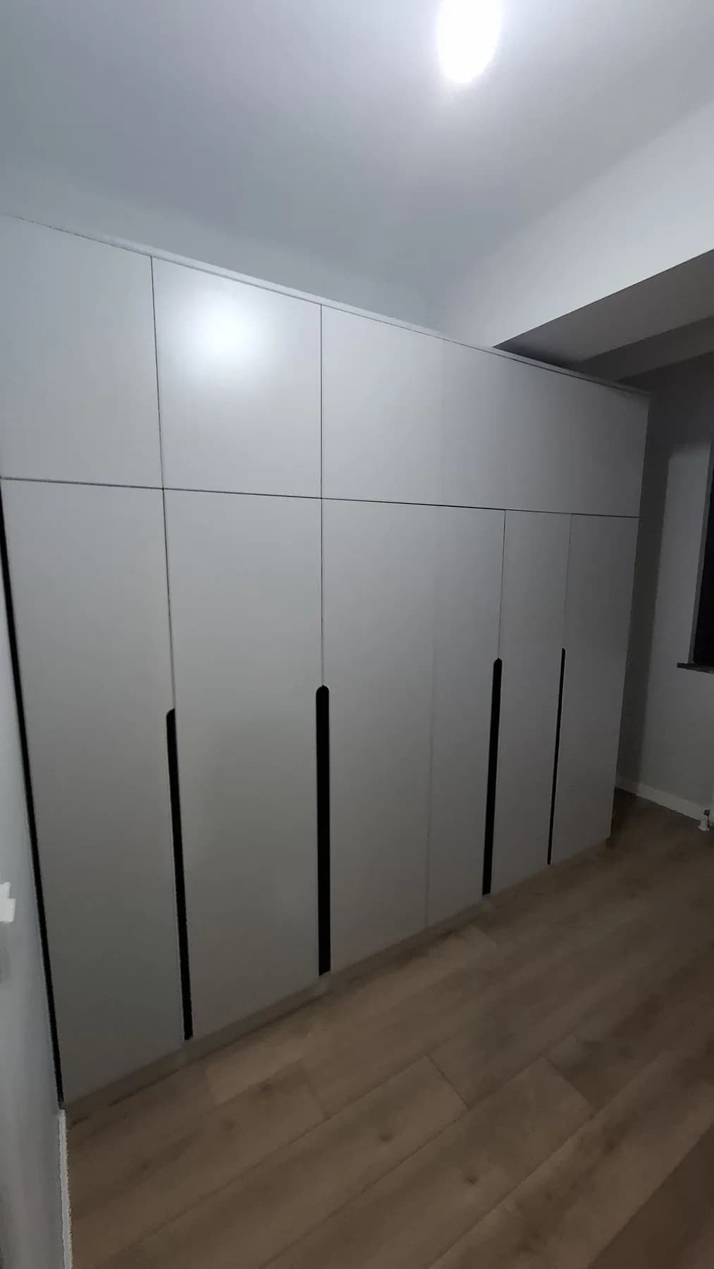 Duvar boyu gri gardırop, ince siyah kulplar